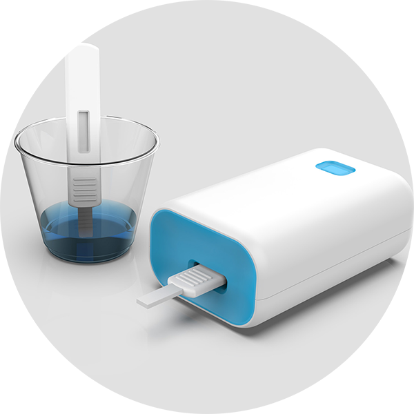 Consumer device for BARDA, electronic device with a test strip next to a clear cup containing blue liquid.