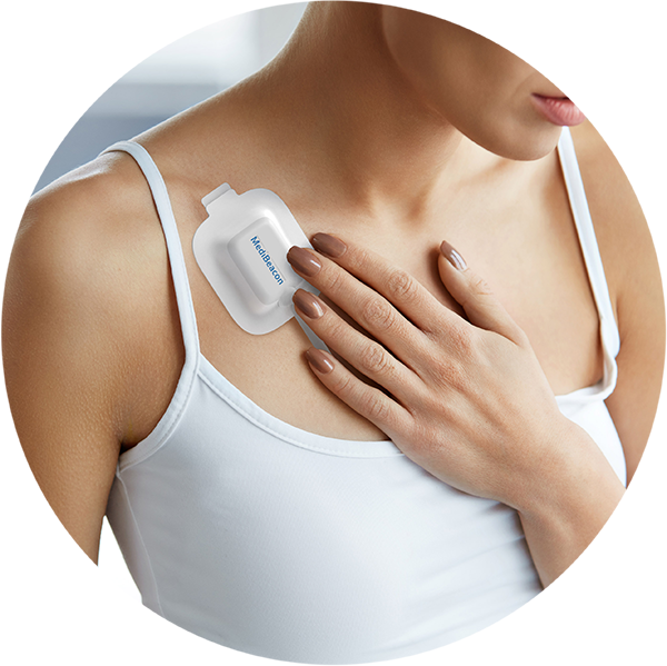 A person in a white tank top applies a MediBeacon wearable sensor to their chest.